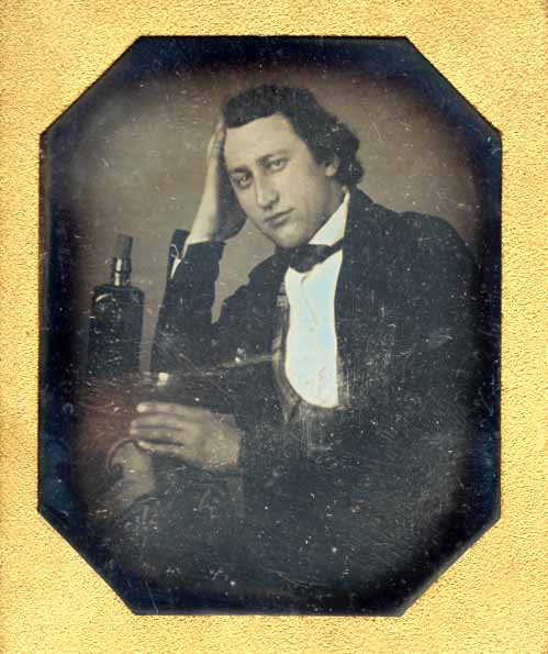 Man with Bitters Bottle Holding Glass of Dark Liquid